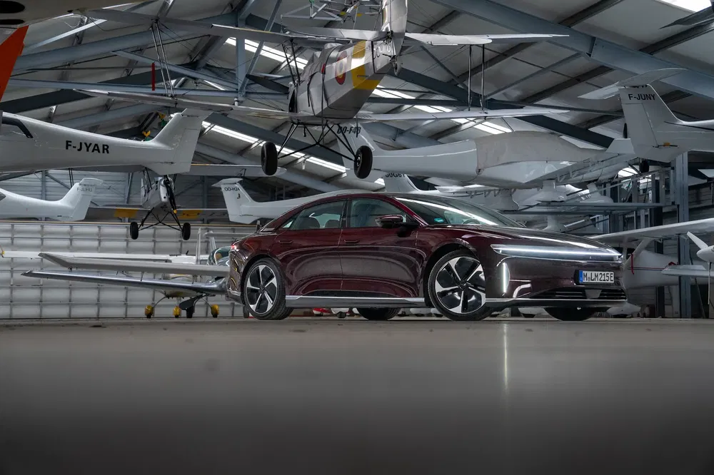 Voiture Lucid Air rouge garée dans un hangar à avions modernes.