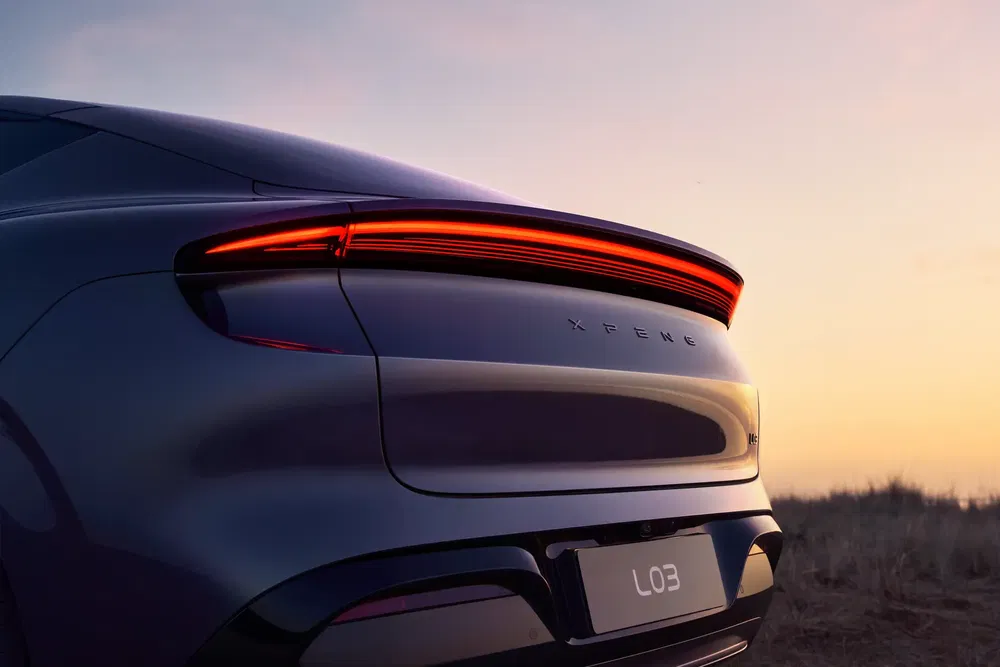 Voiture électrique XPeng L03 avec feux arrière allumés au crépuscule.