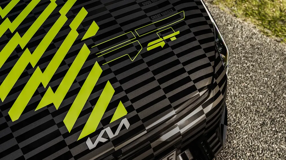 Motif camouflage sur capot d'une Kia moderne avec accents graphiques jaunes.