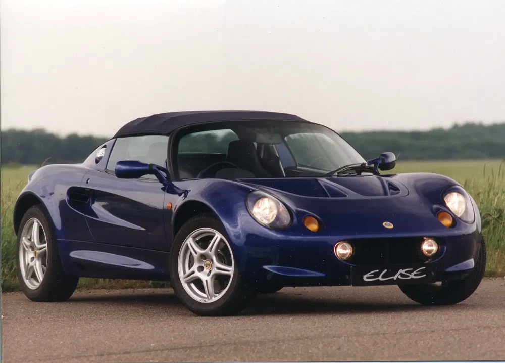Lotus Elise bleu sur route, design élégant et performant, nature en arrière-plan.