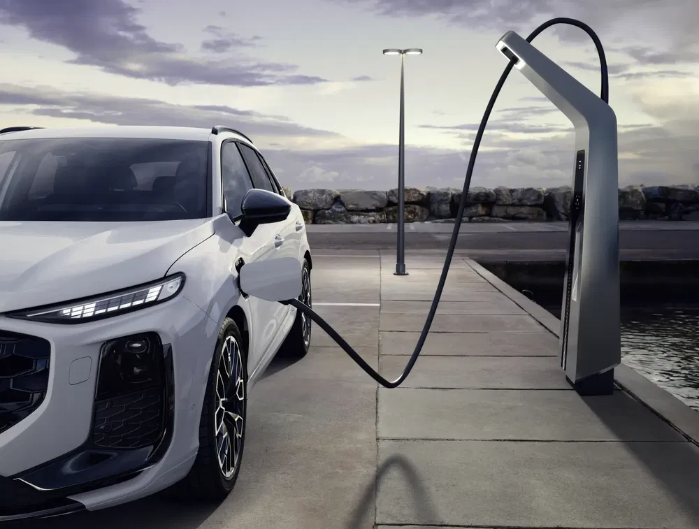 SUV électrique BYD Tang se rechargeant dans une station de recharge moderne au bord de l'eau.