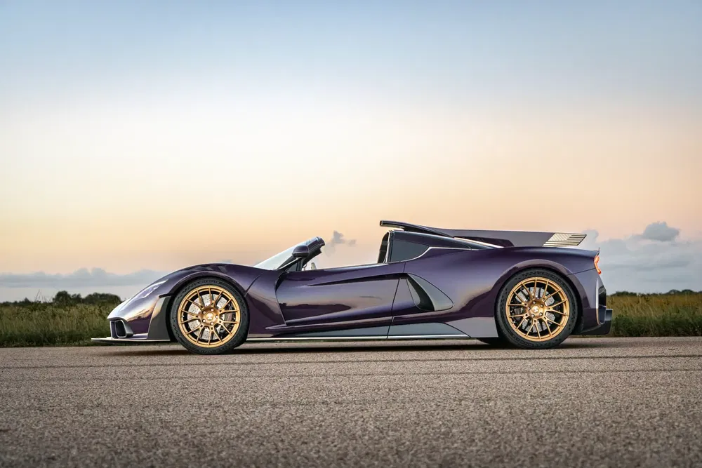 Paarse Hennessey Venom F5 Roadster sportwagen op weg bij zonsondergang.