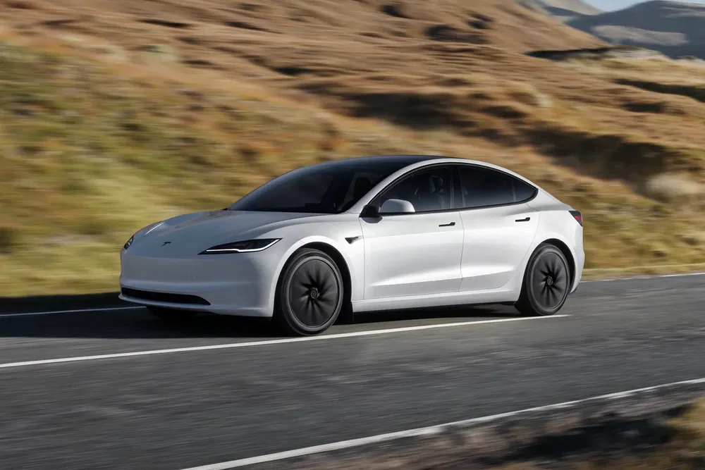 Tesla Model 3 blanche roulant sur une route de campagne pittoresque.