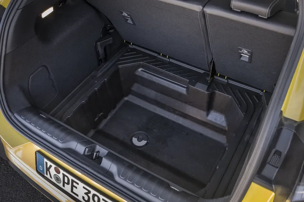 Coffre spacieux d'une voiture Volkswagen avec compartiment de rangement, plaque d'immatriculation visible.