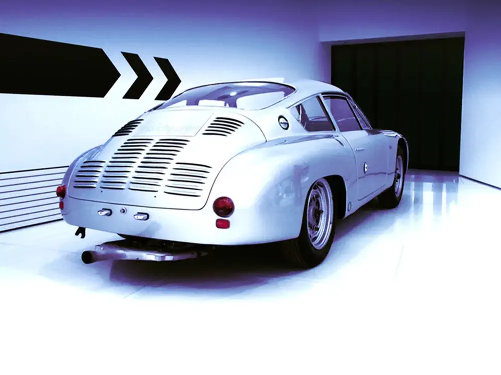Voiture classique argentée dans un showroom aux lignes modernes et éclairage bleu.