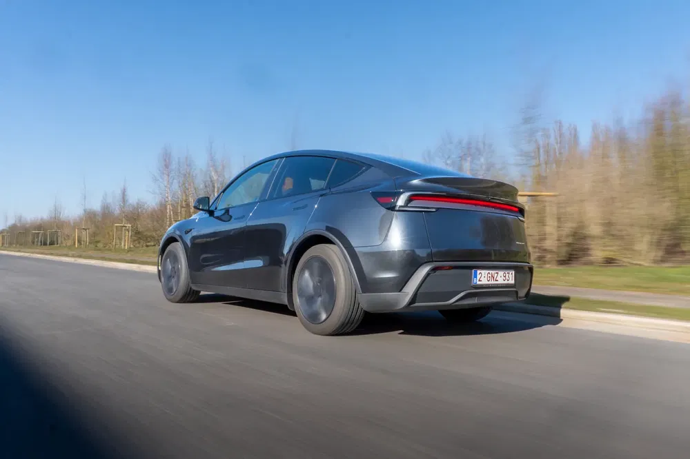 Elektrische auto rijdt op weg, aerodynamisch ontwerp en modern, heldere lucht, vlak landschap.