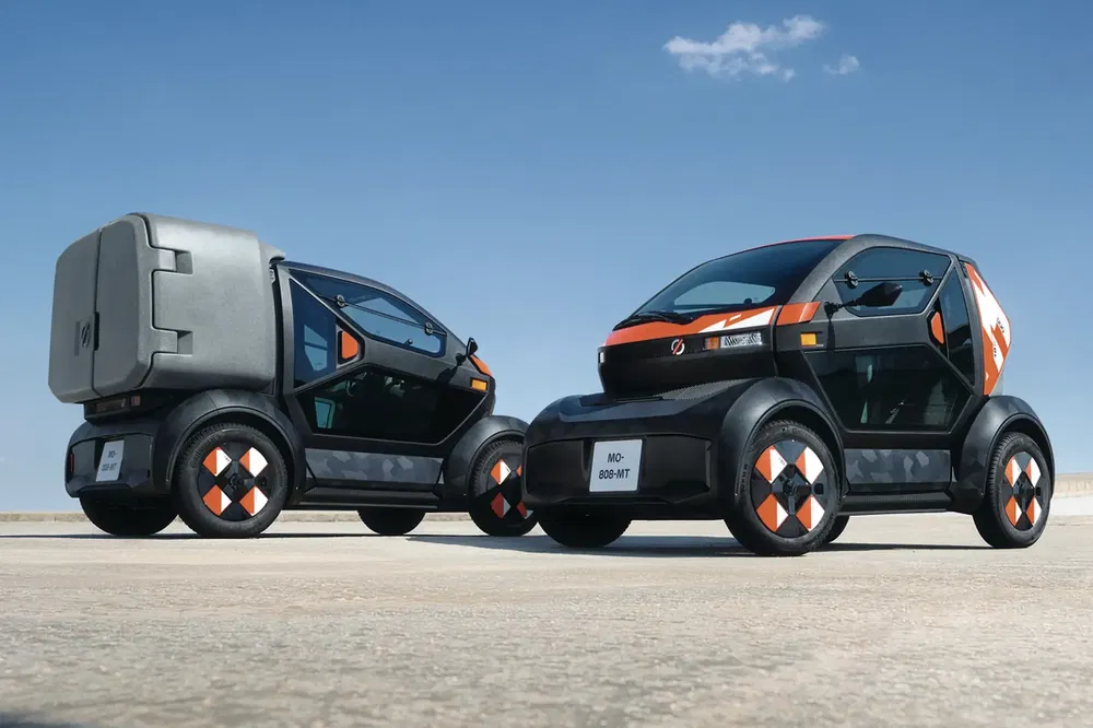 Deux véhicules électriques Microlino compacts sur fond de ciel bleu clair.