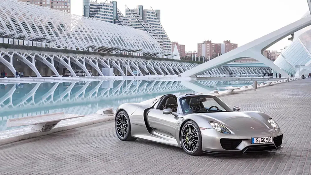 Porsche 918 Spyder argentée stationnée devant l'architecture futuriste de Valence.