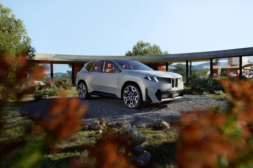 Moderne elektrische BMW SUV geparkeerd in een zonnige binnenplaats omgeven door groen.