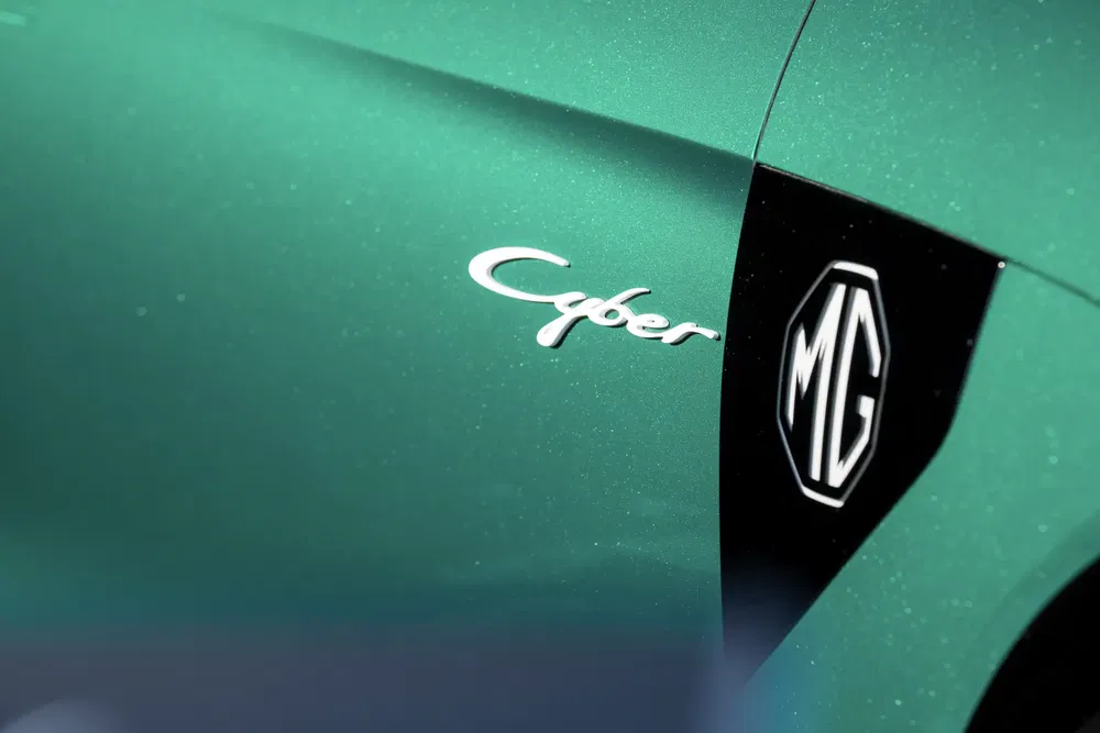 Logo MG Cyber sur carrosserie verte métallique d'une voiture de sport moderne.