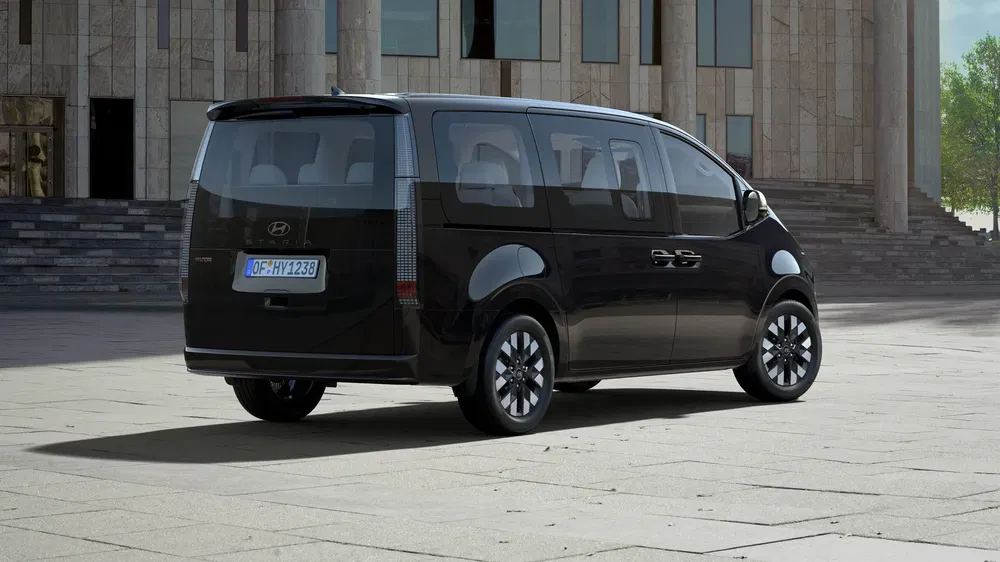 Hyundai Staria zwarte geparkeerd voor modern gebouw, elegante en ruime ontwerp.
