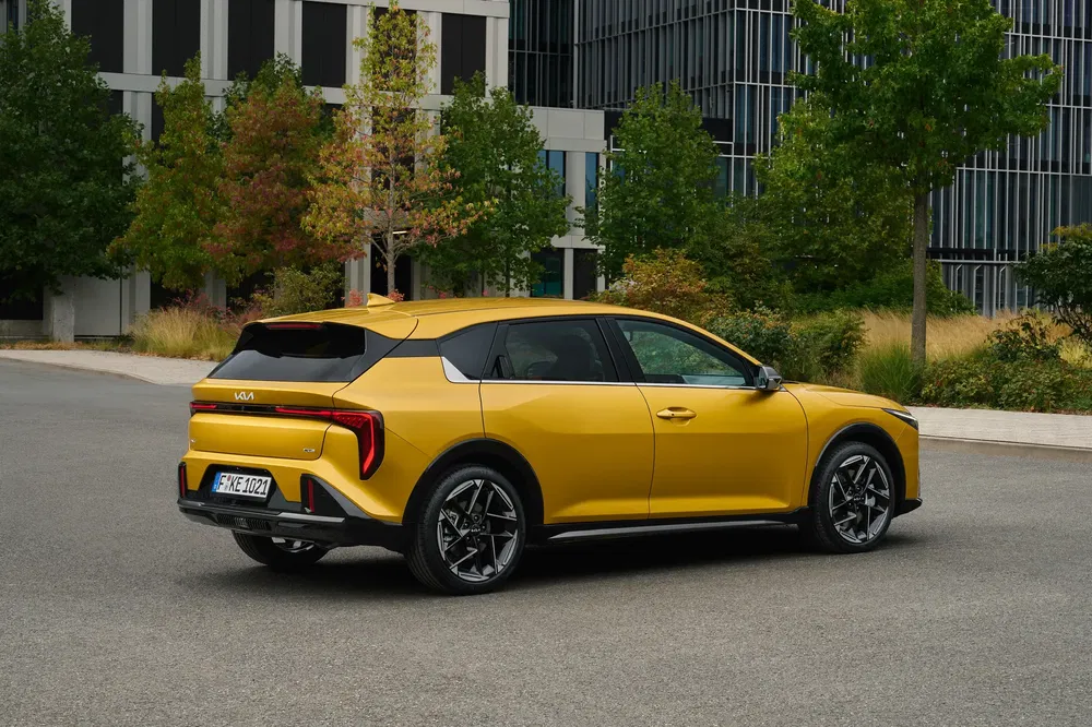 Kia EV6 jaune garée devant un immeuble moderne, arbres en arrière-plan.