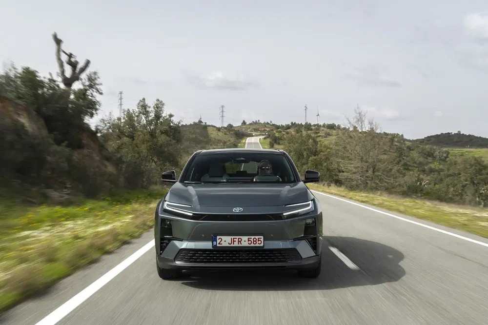 Toyota bZ4X rijdt op een landelijke weg, omringd door weelderige landschappen.