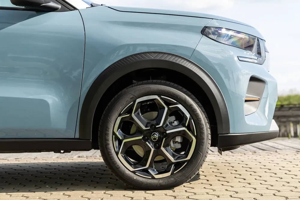Vue latérale de la roue avant d'une Citroën C3 Aircross bleue sur pavé.
