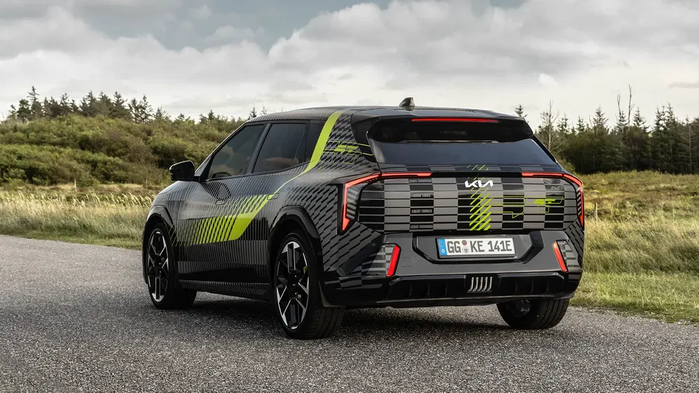 Kia EV9 sur route de campagne, design futuriste, arrière rayé noir et jaune.