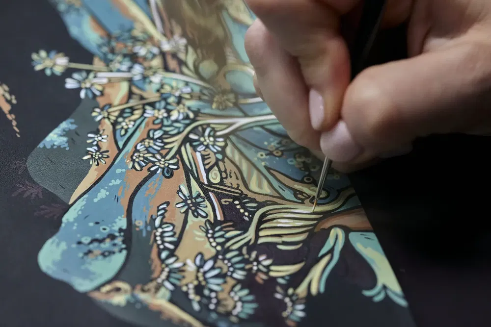 Main peignant une illustration complexe de fleurs et motifs naturels avec précision.