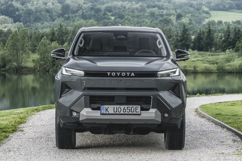 Toyota pickup gris devant un paysage verdoyant et un lac paisible.