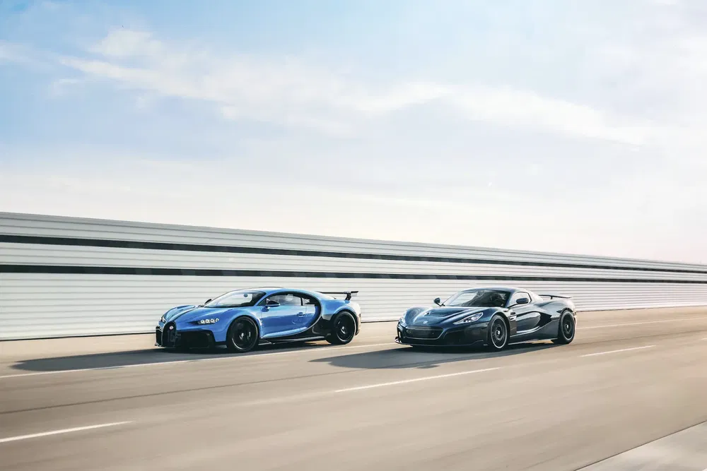 Bugatti Chiron bleue et Rimac C_Two grise en course sur une route dégagée.