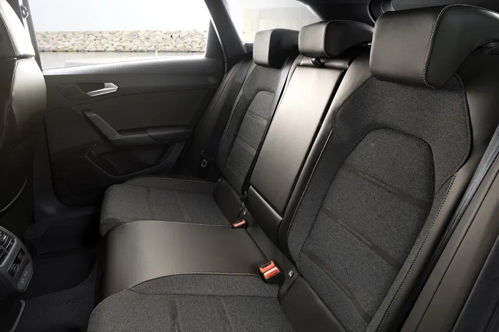 Intérieur arrière de la Volkswagen Passat, sièges en tissu sombre et accoudoir central.