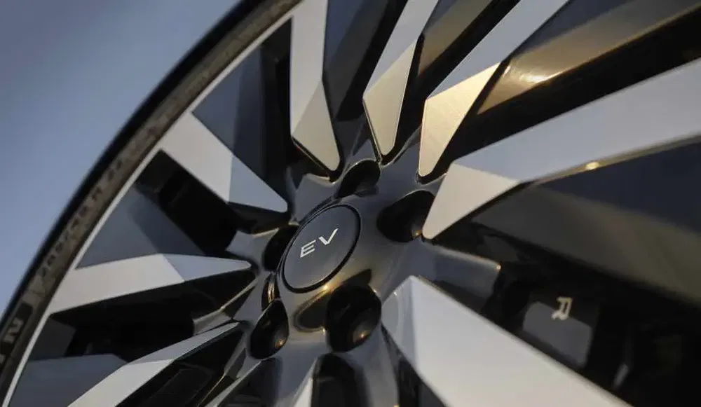 Gros plan sur une jante de voiture électrique brillante avec badge EV au centre.