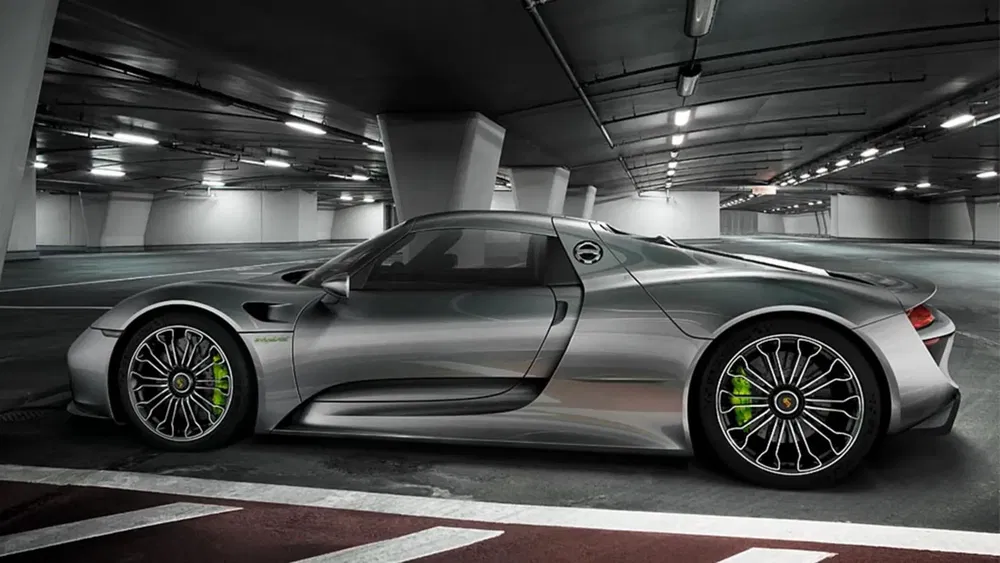 Porsche 918 Spyder grise stationnée dans un parking souterrain moderne.