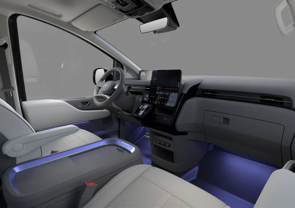 Moderne Hyundai bestelwagen interieur met blauwe sfeerverlichting en groot touchscreen.