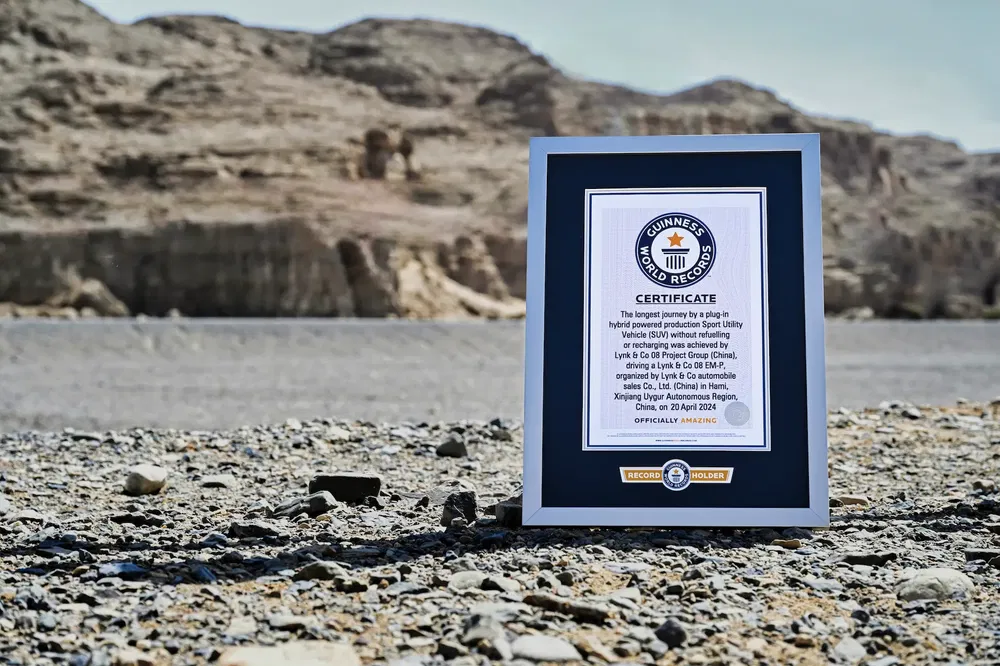 Certificat du record du monde Guinness posé sur sol rocheux, montagnes en arrière-plan.