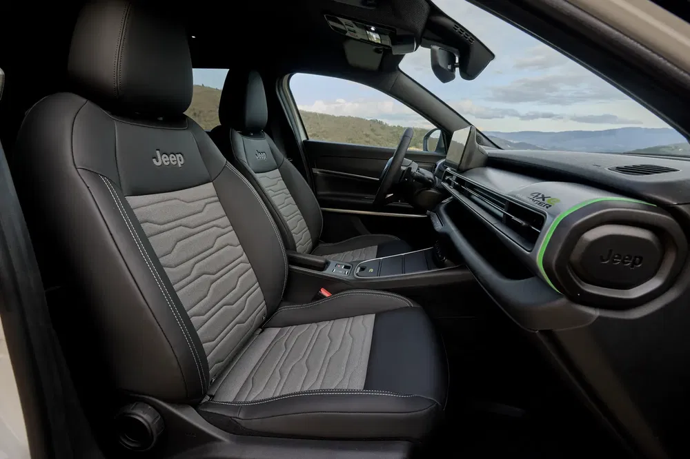 Intérieur d'une Jeep avec sièges cuir noir, vue sur le tableau de bord moderne.