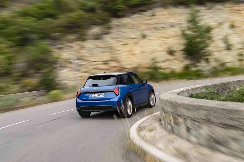 Mini Hatch bleue sur route sinueuse, démontrant agilité et performance en conduite dynamique.
