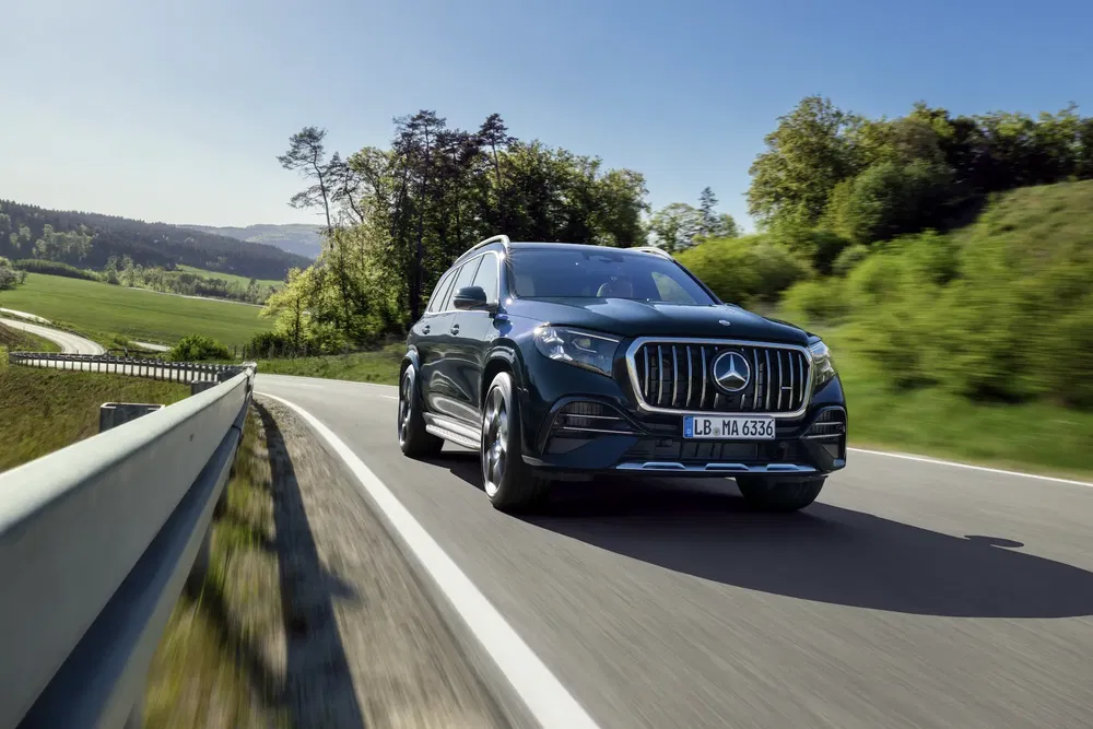 Mercedes-Benz GLS se déplaçant sur une route de campagne bordée d'arbres et de champs verdoyants.