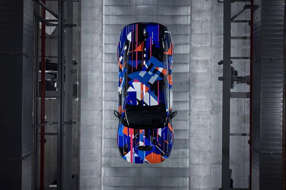 Voiture avec un design camouflage géométrique coloré vue d'en haut dans un atelier.