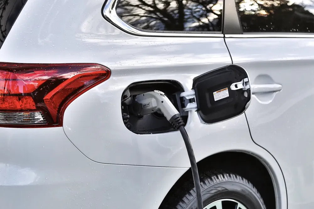 Elektrische Mitsubishi Outlander wordt opgeladen, kabel aangesloten op achteraansluiting.