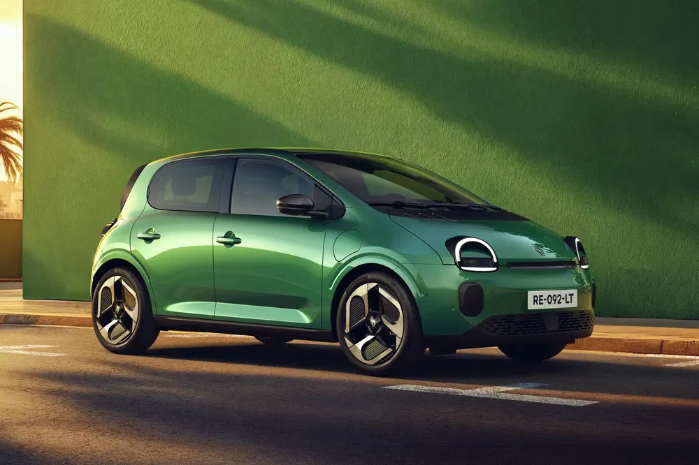 Voiture électrique compacte verte garée devant un mur vert ensoleillé, design moderne et futuriste.