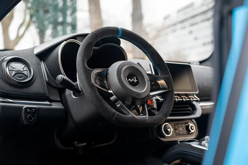 Interieur van een moderne Alpine met sportstuur, high-tech dashboard en blauwe accenten.