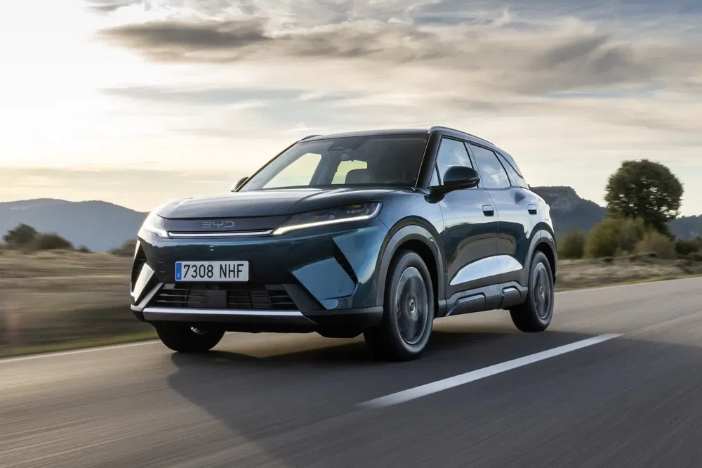 {"fr":"BYD SUV bleu foncé roulant sur une route de campagne au coucher du soleil.","nl":"Donkerblauwe BYD SUV rijdend op een landelijke weg bij zonsondergang."}