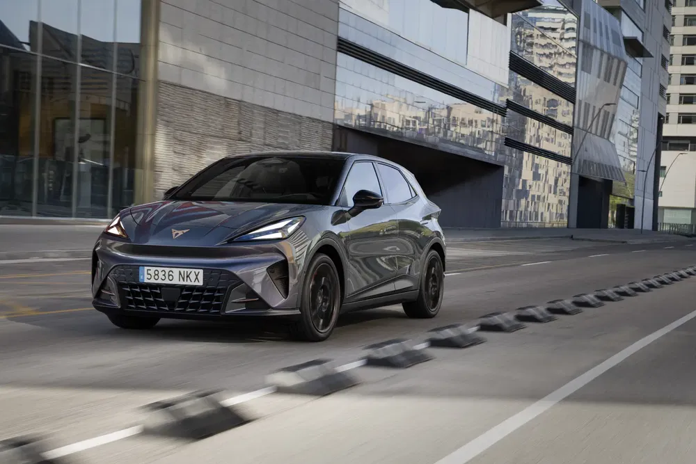 Cupra Tavascan SUV gris foncé sur route urbaine moderne.