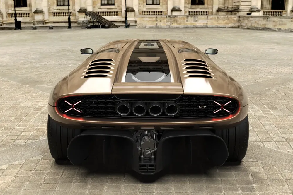 {"fr":"Vue arrière d'une supercar Bugatti bronzée, GTT, avec détails d'échappement et design aérodynamique.","nl":"Achteraanzicht van bronzen Bugatti supercar GTT, met uitlaatdetails en aerodynamisch ontwerp."}