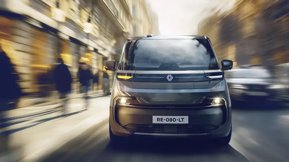Renault van moderne roulant en milieu urbain flou, phares LED allumés.