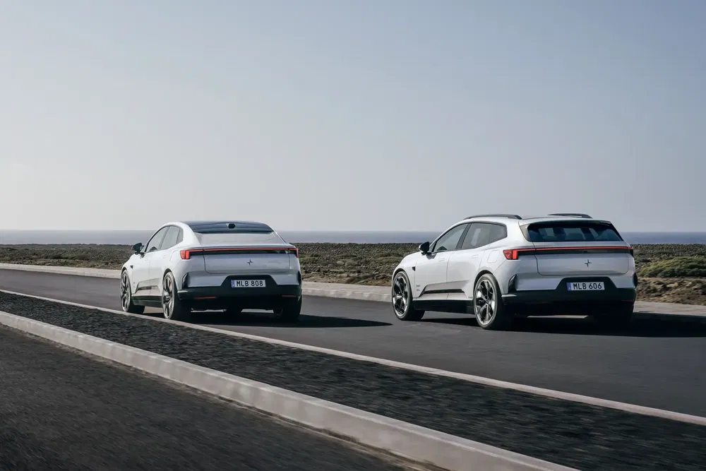 Deux voitures électriques Polestar 2 blanches roulant sur une route côtière dégagée.
