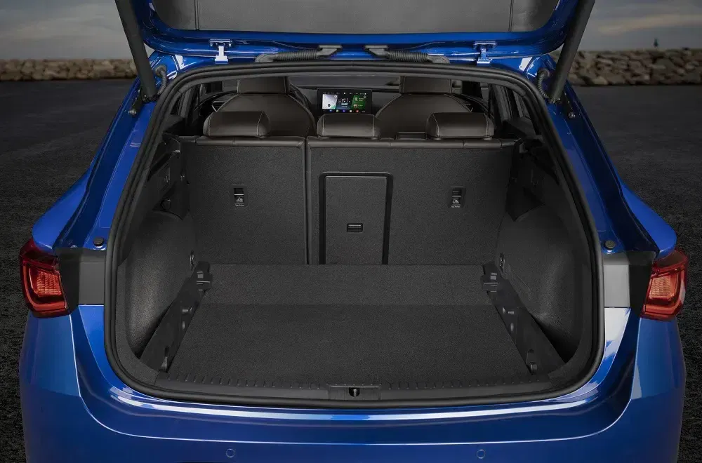 Coffre spacieux d'un véhicule bleu à hayon ouvert avec sièges arrière rabattables.