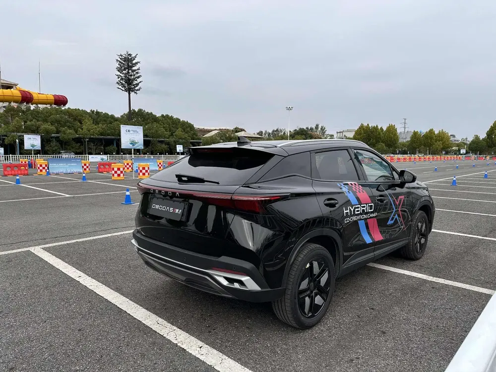 SUV Chery Omoda 5 noir, stationné sur un parking, avec design hybride affiché.