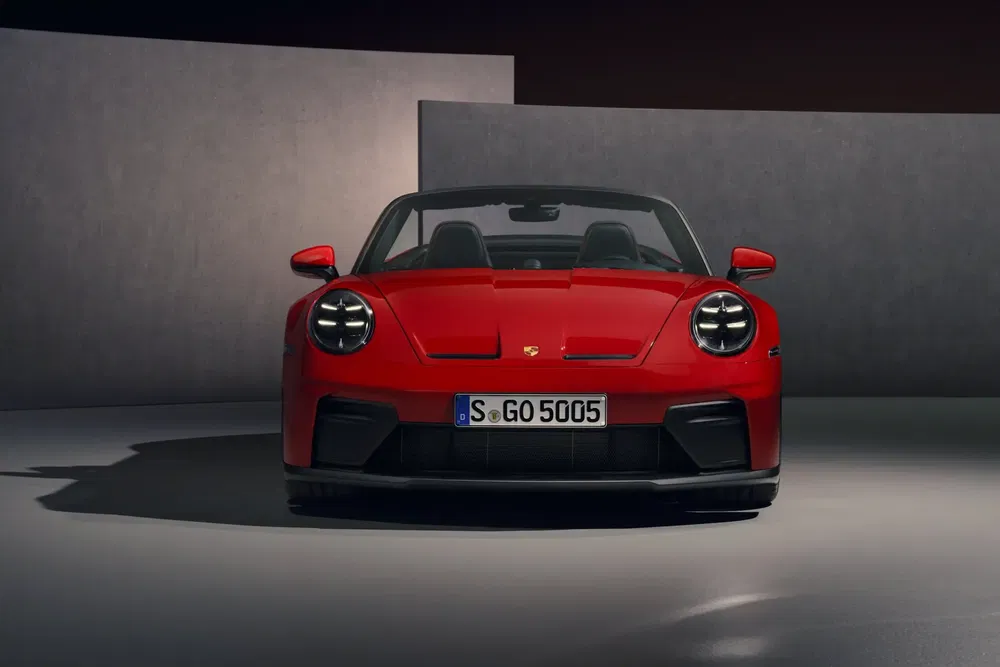 Porsche 911 rouge vue frontale, design moderne et élégant sous faible éclairage.