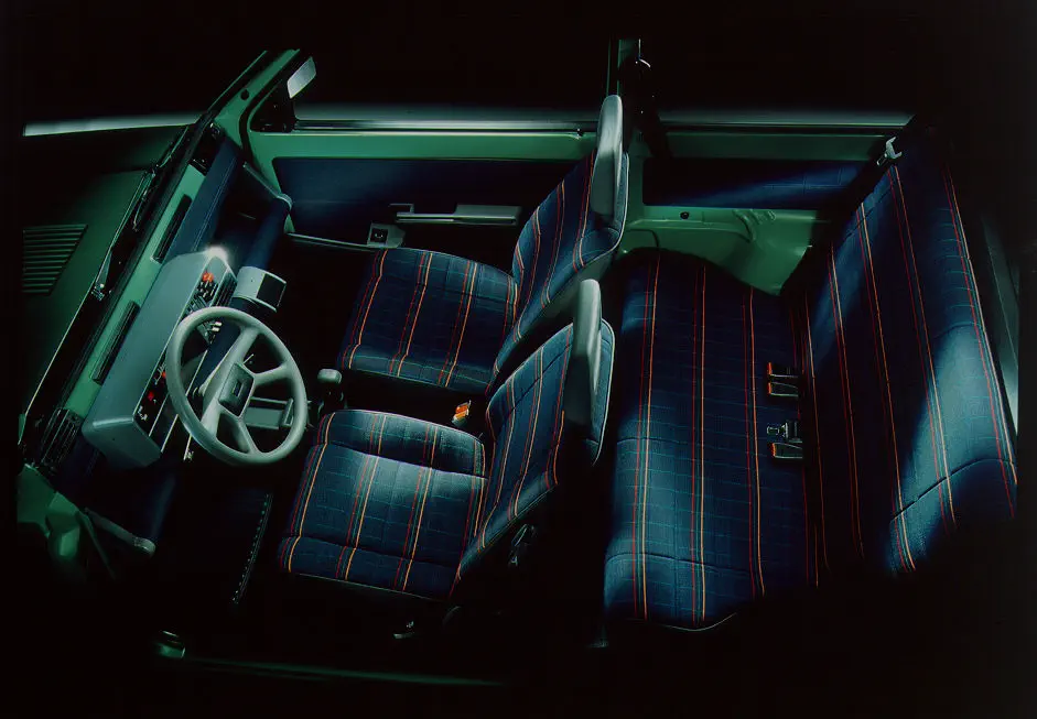 Retro auto-interieur met blauw-rood geruite stoelen en klassiek dashboard.