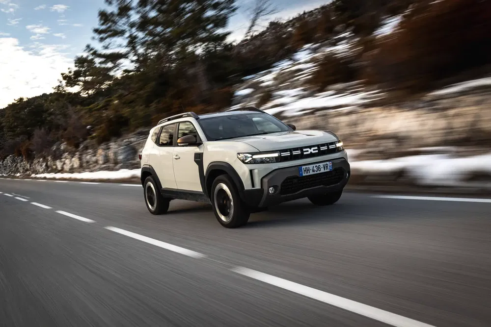 SUV Dacia Duster roulant sur une route de montagne enneigée.