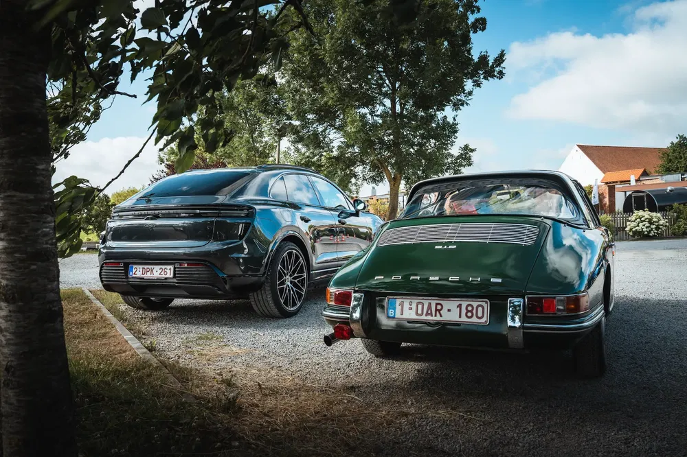 Porsche Cayenne moderne et classique 911 garées côte à côte dans une allée ensoleillée.