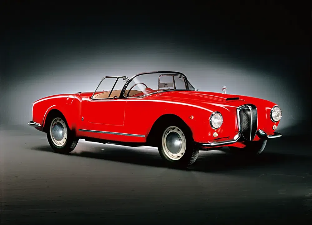 Lancia Aurelia B24 rouge classique, décapotable élégante en studio sur fond sombre.