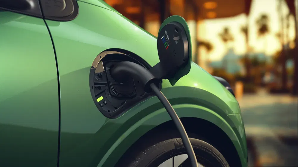 Station de chargement pour voiture électrique verte avec connecteur branché en gros plan.