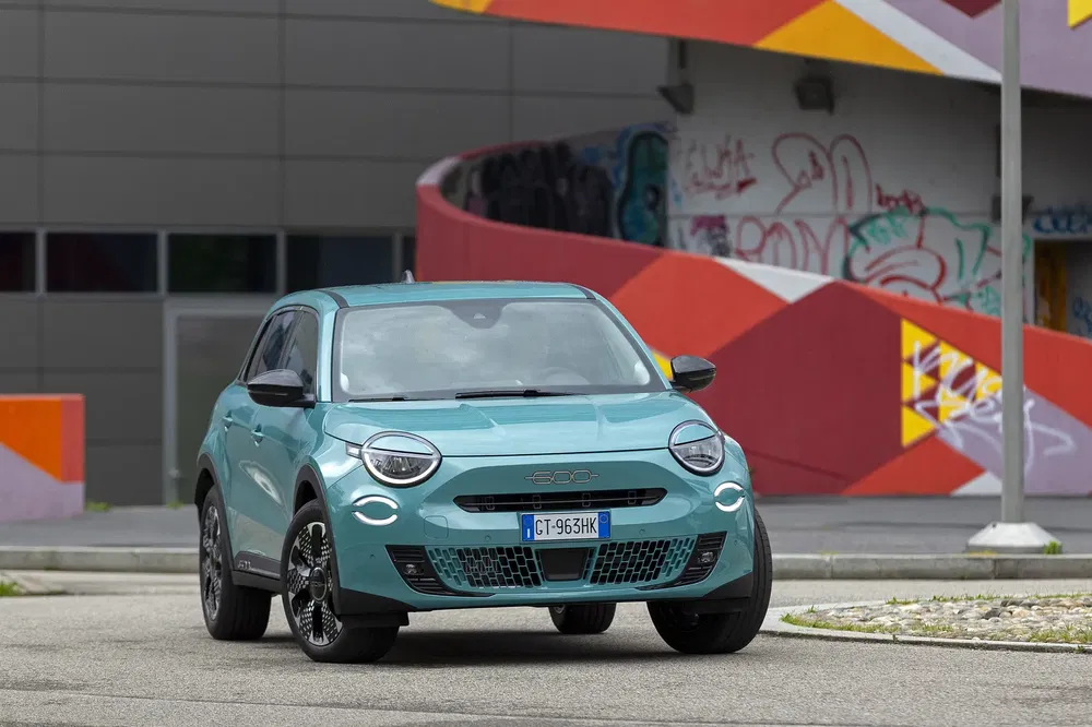 Mintgroene elektrische Fiat 500 voor kleurrijke met graffiti versierde stadsachtergrond.