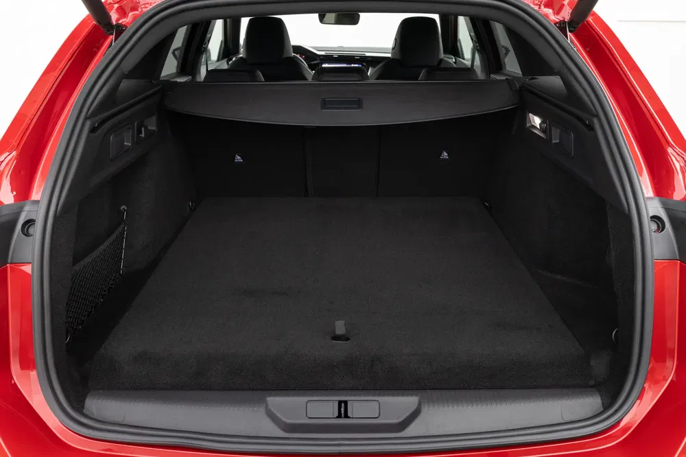 Ruime kofferbak van een rode auto, achterstoelen neergeklapt voor maximale laadruimte.