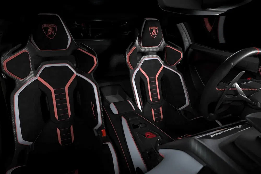 Intérieur Lamborghini moderne avec sièges sportifs noirs et garnitures rouges élégantes.